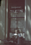 115657 Afbeelding van een jongen zittend in het raam van het Antiquariaat Trajectina (Ambachtstraat 2) te Utrecht.